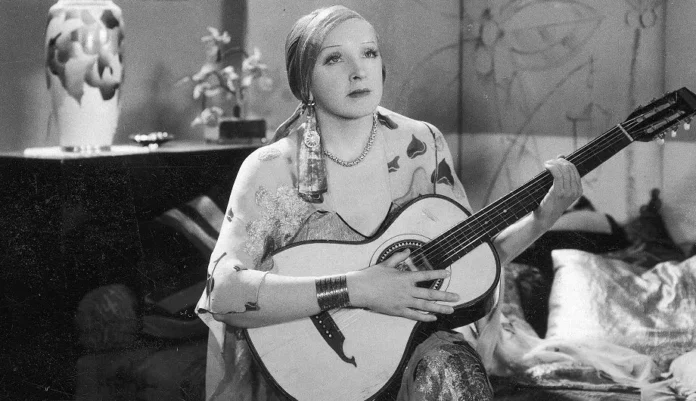 Hanka Ordonówna jako Rita Holm, śpiewaczka i agentka wywiadu gra na gitarze w jednej ze scen filmu